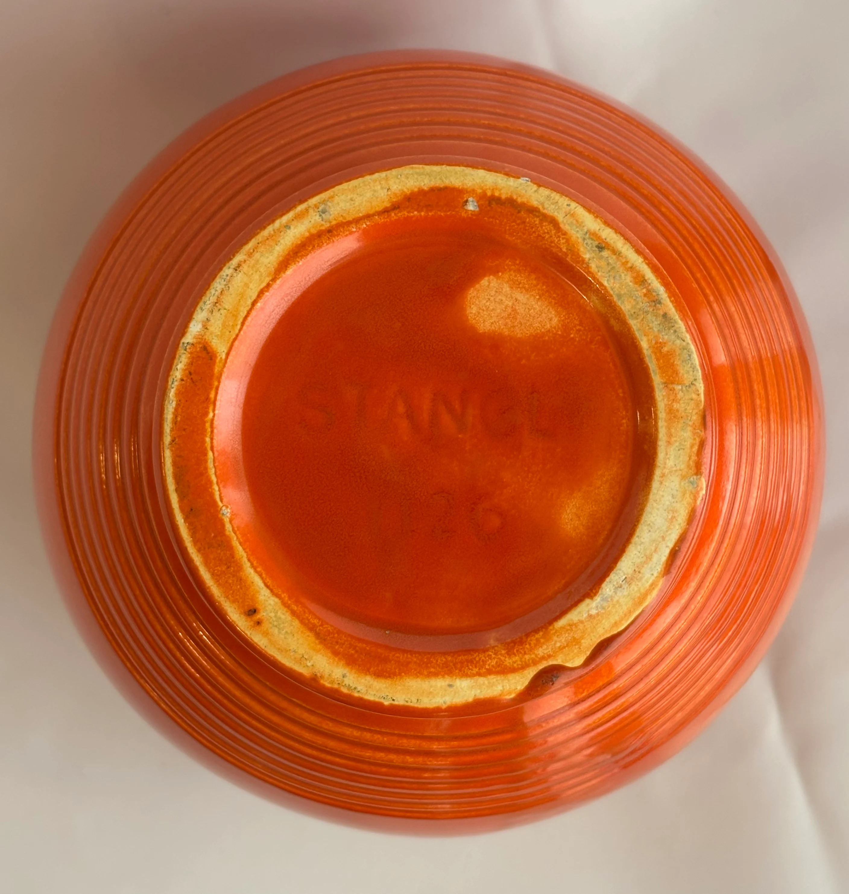 A maker’s stamp impressed on the base of a pottery vase.