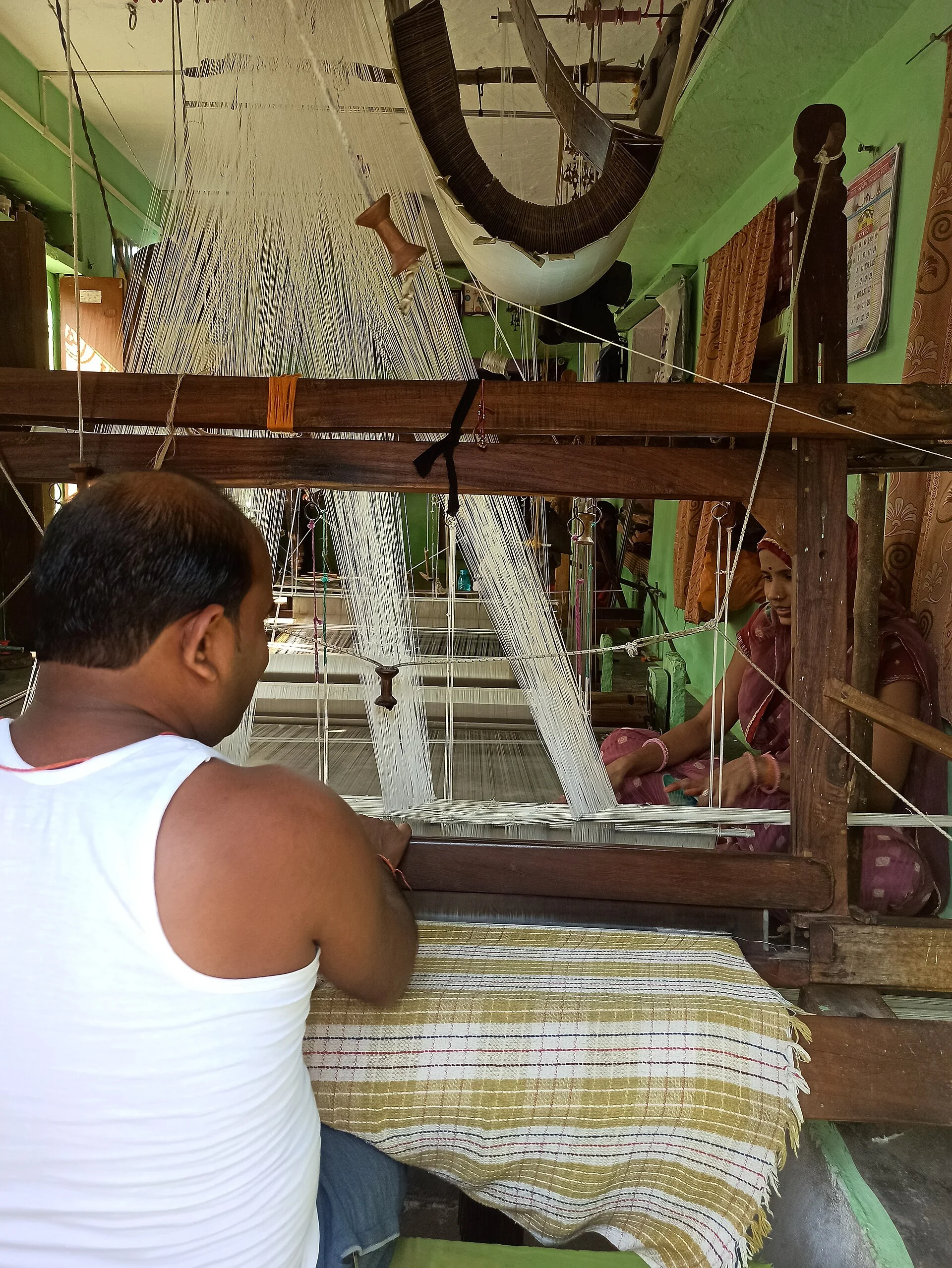 A textile artisan works at a loom making a sari.