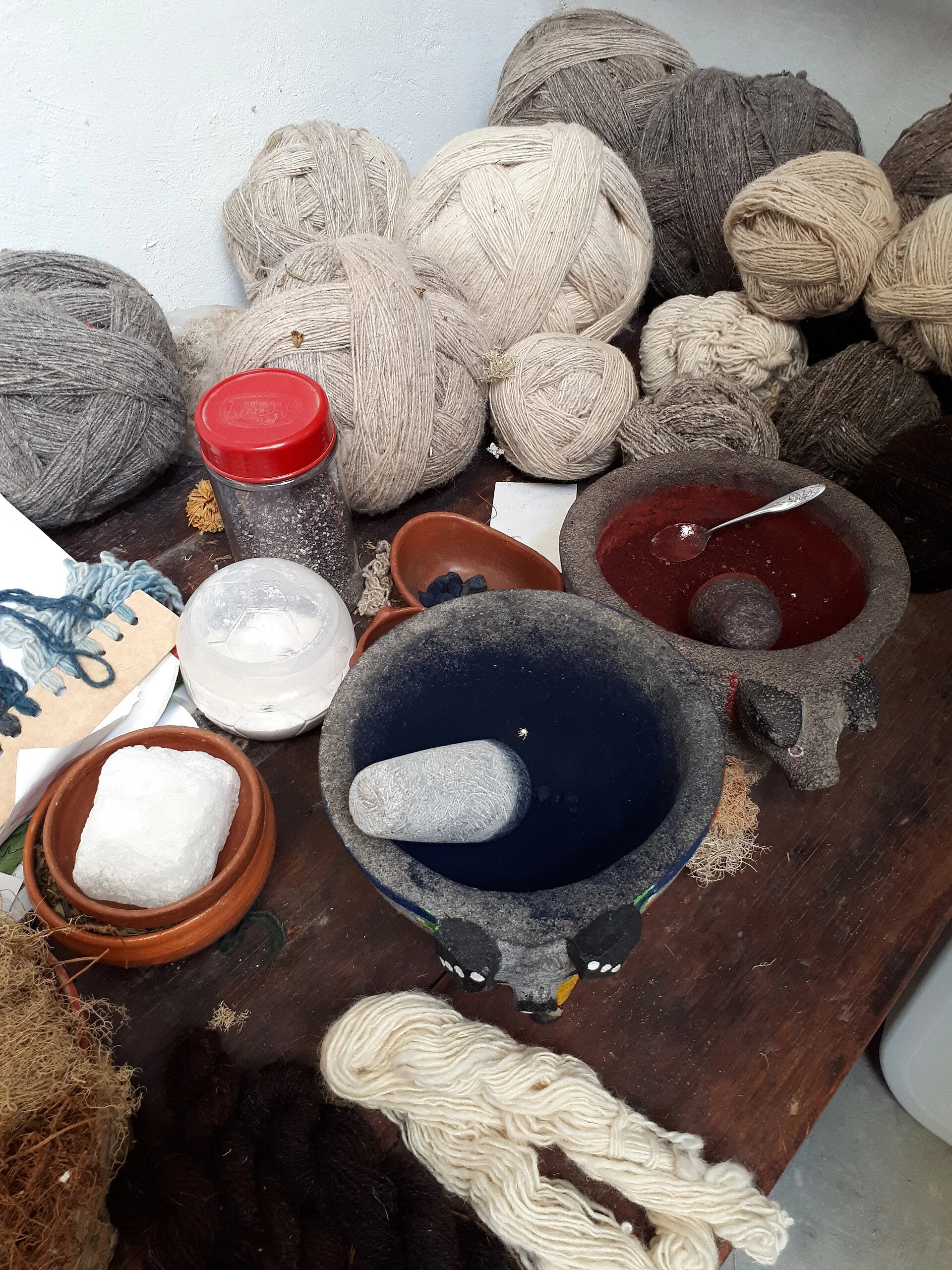 Natural dye materials and coloured yarn arranged in a textile workshop.