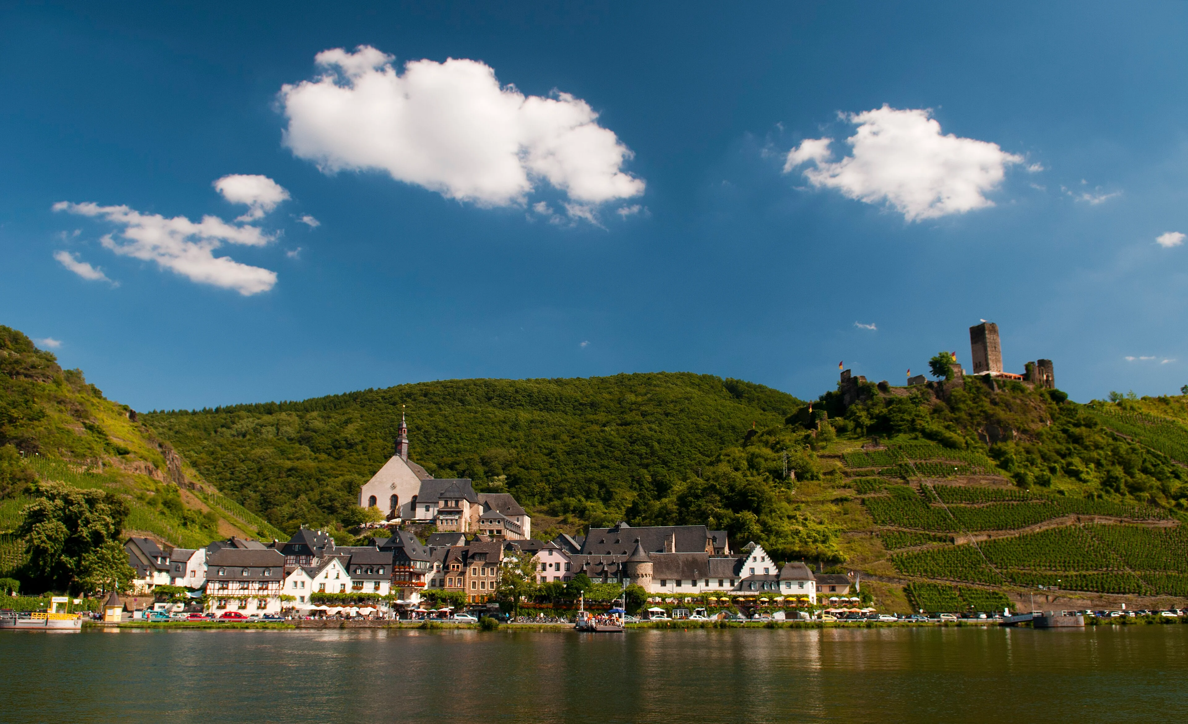 Steep green vineyards rise above clustered roofs beside the Mosel at Beilstein.