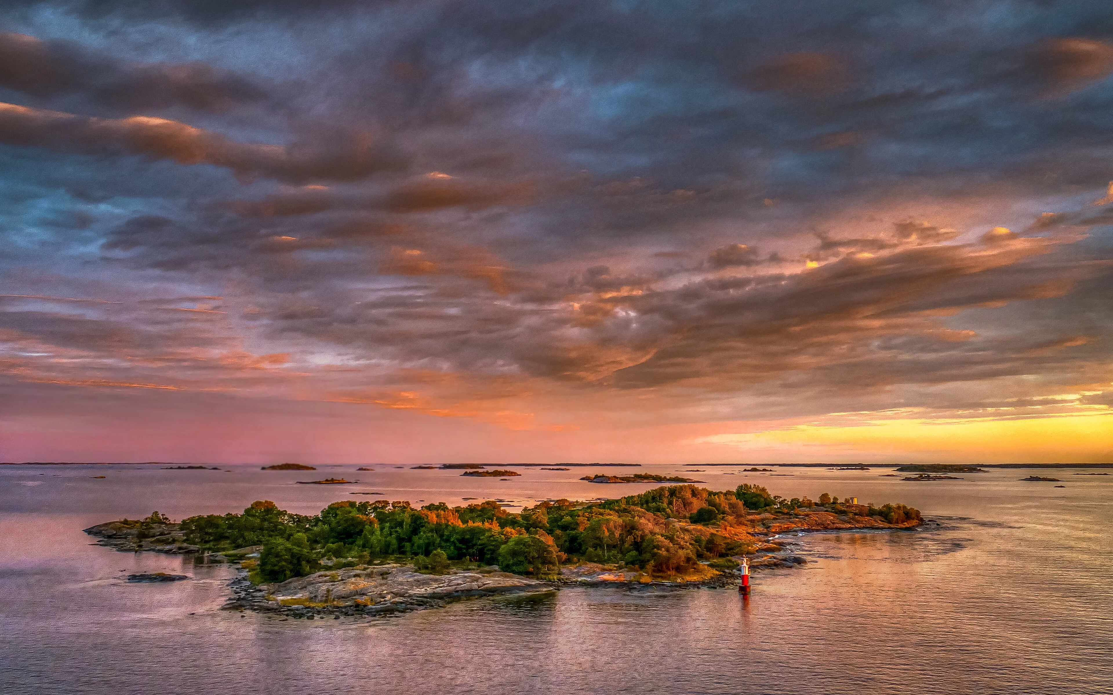 Low evening sunlight crosses the water and wooded islands of the Stockholm archipelago.