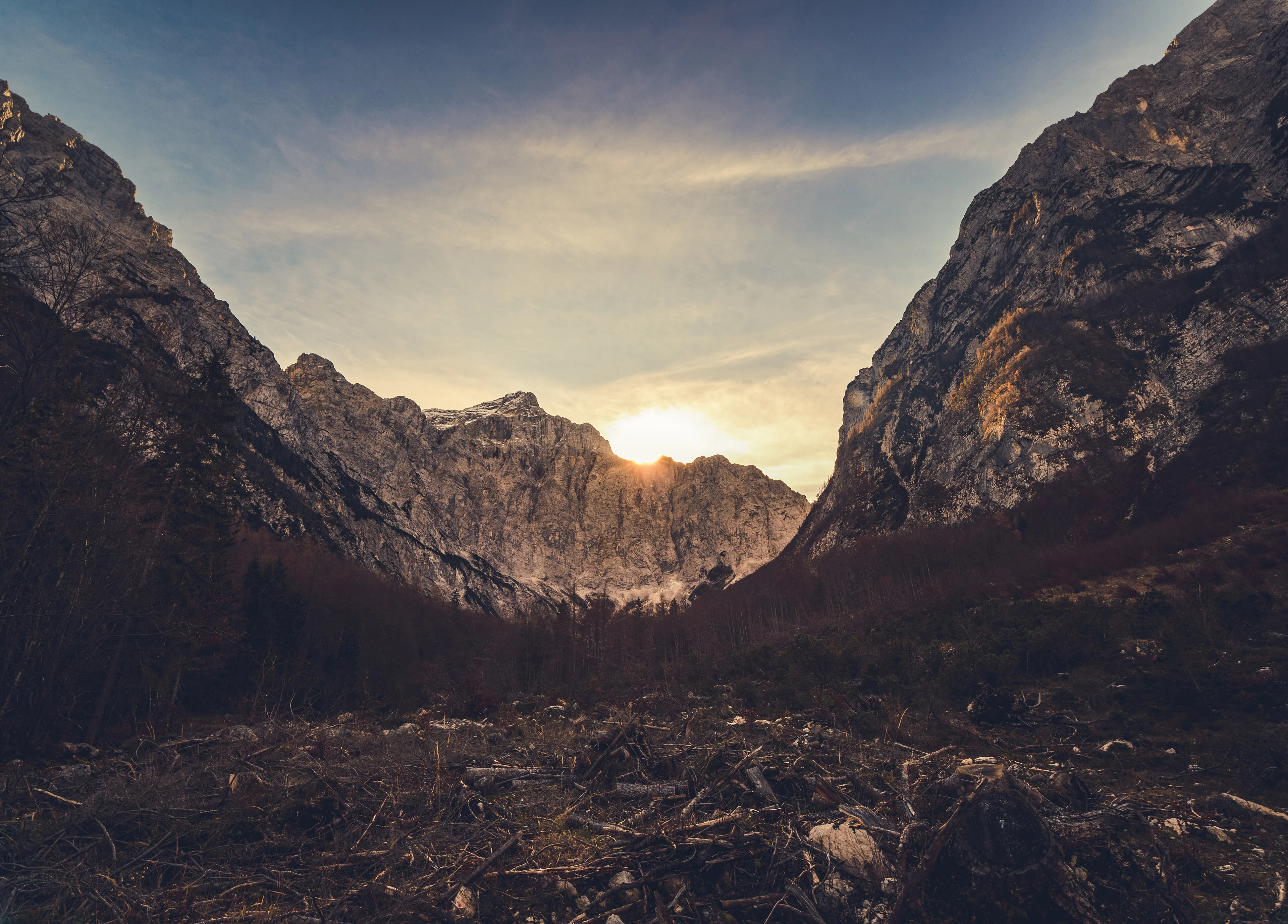 Layers of mountain fade into haze beneath a warm sunset over Triglav.
